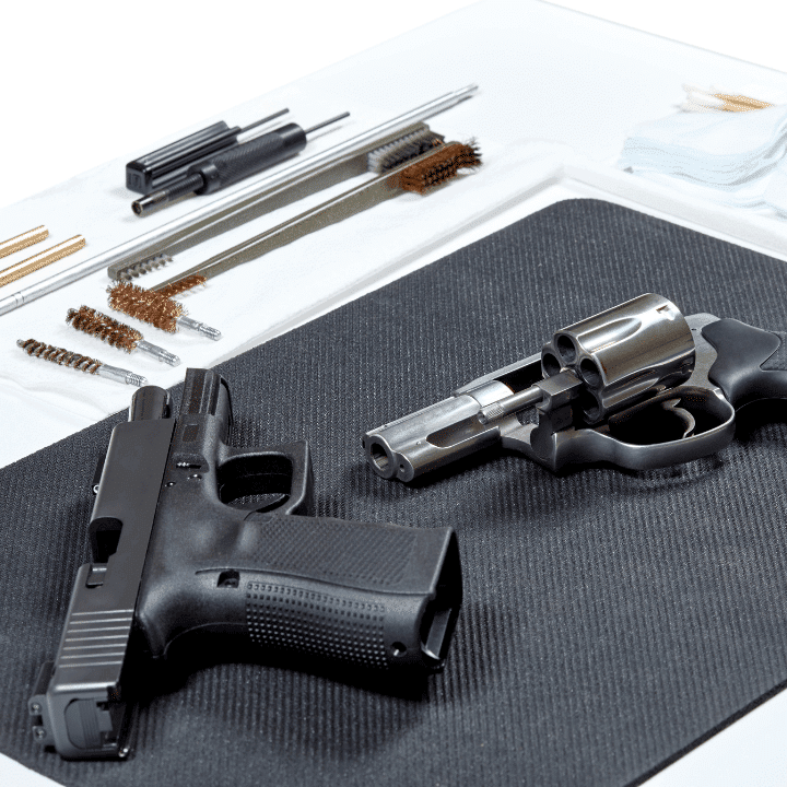 This image shows two handguns laying on a table and there's a handgun cleaning kit laid out next to them.