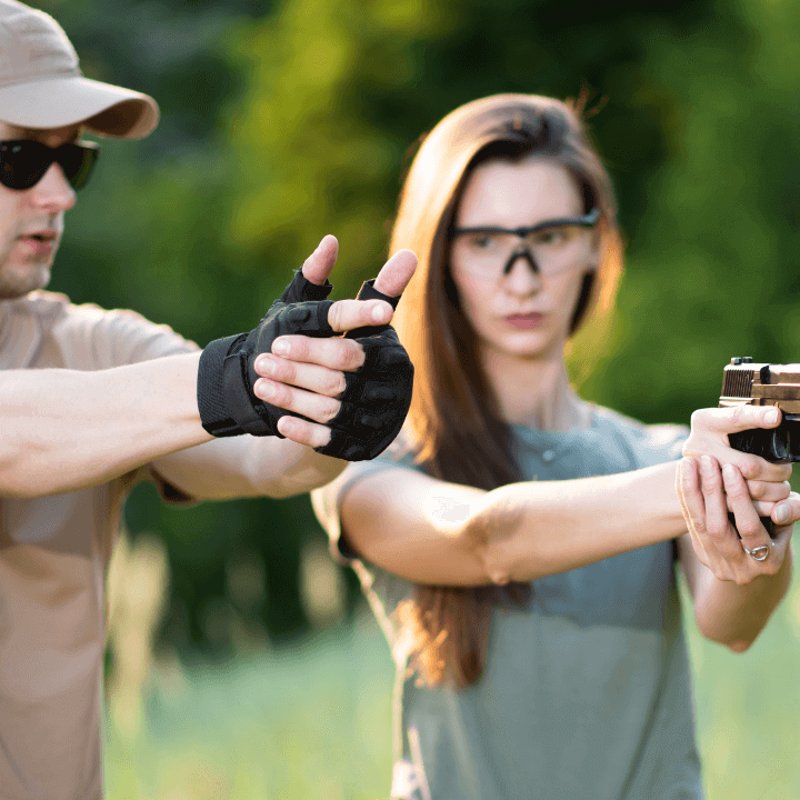 This image shows a handgun safety instructor teaching a woman how to properly hold a gun.
