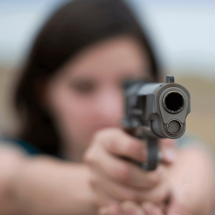 This image shows a woman holding a gun and pointing it directly in front of her.