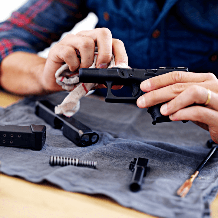 A picture of someone cleaning the parts of a handgun.