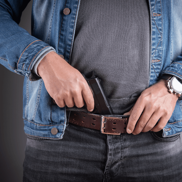 A picture of someone with their hand on a concealed carry gun.