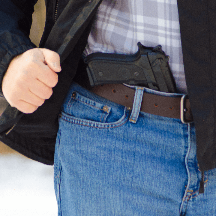 A closeup photo of a man with a gun in his belt