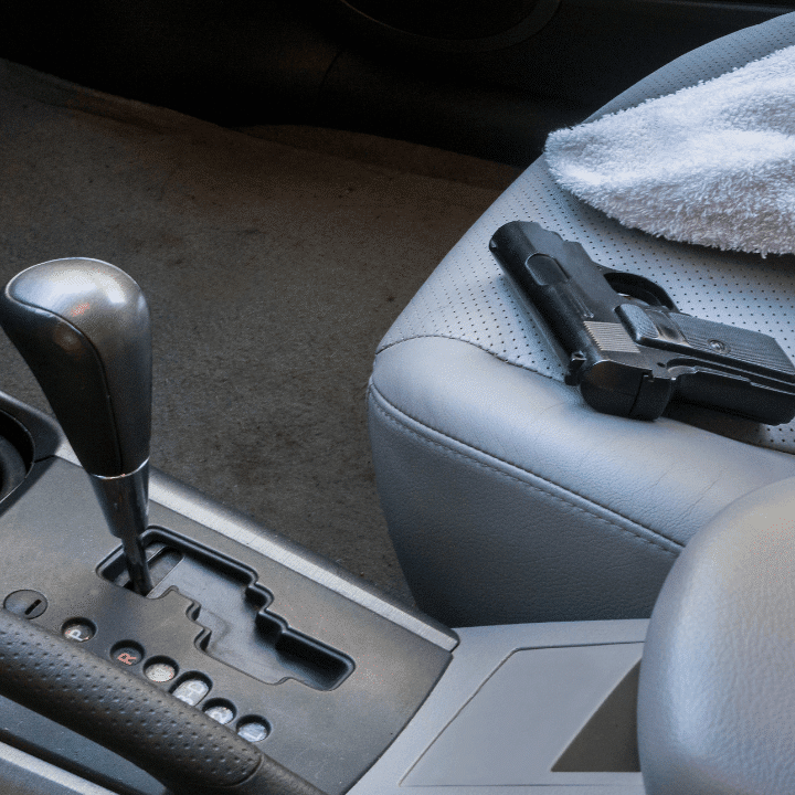 A handgun sitting on a passenger seat in a vehicle