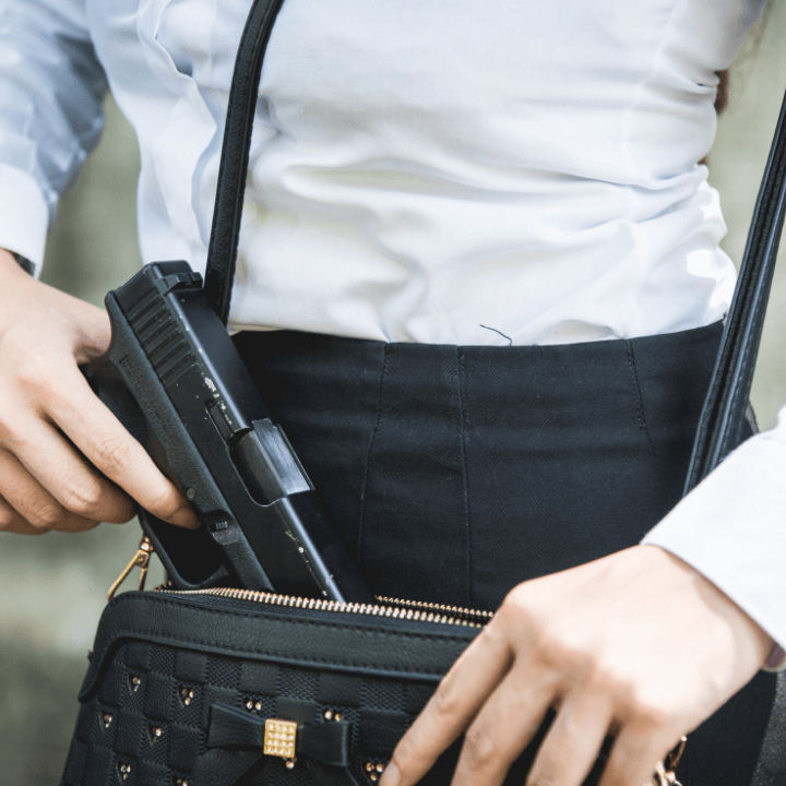 A woman inserting a gun into her purse to conceal it from view