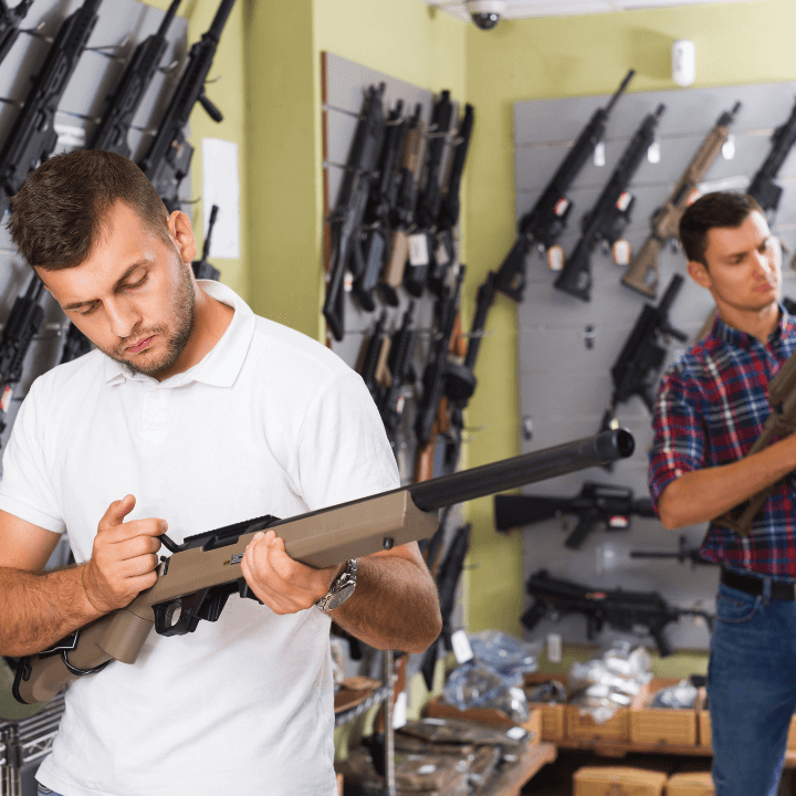 Two men holding guns inside of a gun store