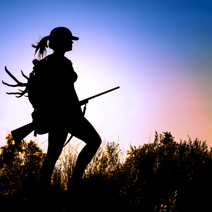 A silhouette of a woman with a gun standing in a field