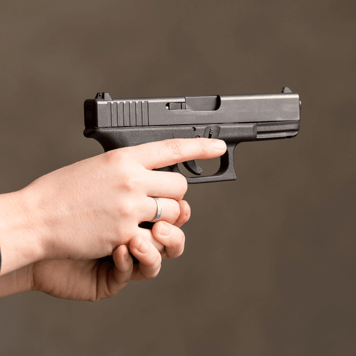 A closeup photo of a woman holding and pointing a gun