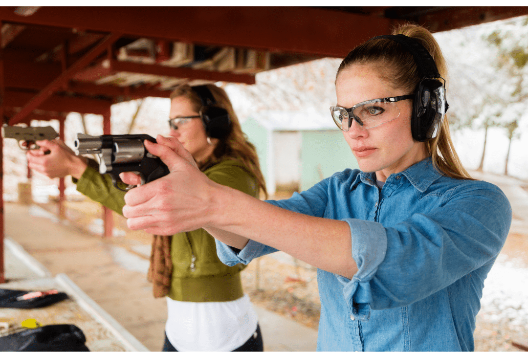 Two women practice shooting at a firing range.